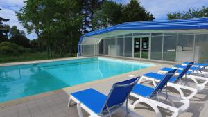 a swimming pool with blue chairs and a building at VVF Piriac-sur-Mer Bretagne Sud in Piriac-sur-Mer
