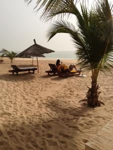 two people sitting on the beach under an umbrella at Appartement à Saly in Saly Portudal