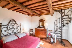 a bedroom with a red bed and a spiral staircase at Agriturismo La Sala in Greve in Chianti