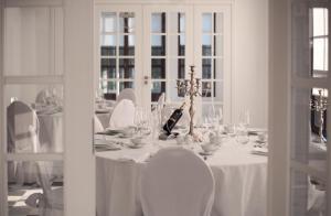 a white table with white chairs and a bottle of wine at Martiany 21 in Martiany