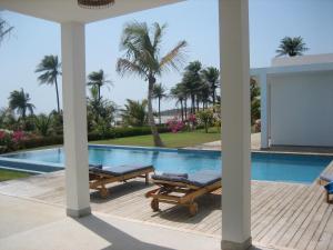 a swimming pool with two chaise lounges next to a house at Amigo 2 in Cap Skirring