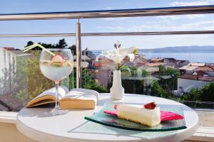 a table with a plate of cake and a glass of wine at Villa Palloma in Baška Voda