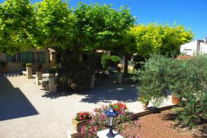 einen Garten mit einem Baum und Blumen und einem Straßenlicht in der Unterkunft Gite le Mas de l'Amandier in Saint-Saturnin-lès-Avignon