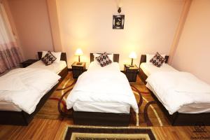 three beds in a room with white sheets and pillows at Aarya Chaitya Inn in Kathmandu