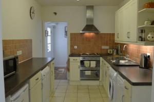 a kitchen with white cabinets and a stove top oven at Nanis in Crantock