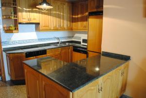 a kitchen with wooden cabinets and a black counter top at APARTAMENTOS RIO MORA 2 in Mora de Rubielos