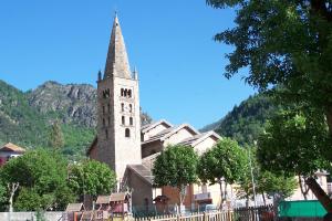 a church with a tall steeple in front of a building at Le Rabuons in Saint-&Eacute;tienne-de-Tin&eacute;e