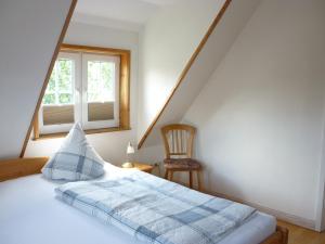 ein Schlafzimmer mit einem Bett, einem Stuhl und einem Fenster in der Unterkunft Pension Sturmmöwe in Norddorf