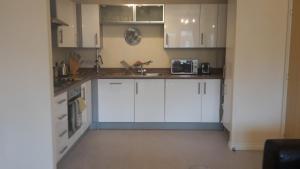 a kitchen with white cabinets and a sink at River view Apartment in Stourport