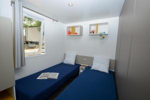 a small room with a blue bed and a window at Camping Le Parc in Saint-Paul-en-Forêt +16 photos