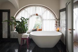 a white bath tub sitting under a window in a bathroom at L'Albereta Relais & Chateaux in Erbusco