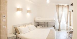 Dormitorio blanco con cama y mesa en Bed & Breakfast AMATI, en Fasano