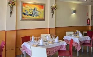 a dining room with white tables and red chairs at Hostal Restaurante Taracena in Yunquera de Henares