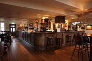 a bar in a pub with wooden floors and bar stools at The Jug And Bottle in Heswall