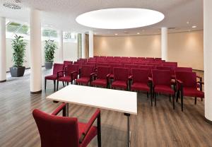 una sala de conferencias con sillas rojas y una mesa blanca en Hotel Raphael im Allgäu en Kempten