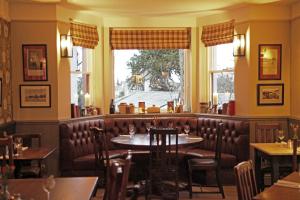 a restaurant with a table and chairs and windows at The Jug And Bottle in Heswall