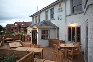 a patio with tables and chairs outside of a building at The Jug And Bottle in Heswall