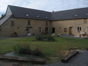 a large brick building with windows and a yard at La Ferme de Montigny (Gite) in Asnières-en-Bessin