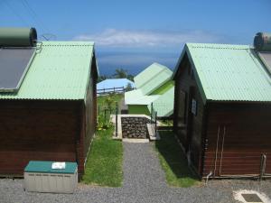 聖若瑟的住宿－Les Vanilliers Location BUNGALOWS，两栋棕色建筑,拥有绿色屋顶和庭院