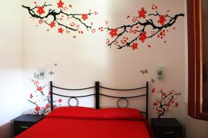 a bedroom with a red bed with a branch with red flowers at B&B da Gio' in Santa Maria la Palma