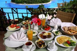 a table with plates of food on a table near a pool at Zeytinada Hotel in Torba