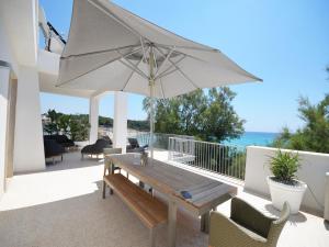a patio with a wooden table and an umbrella at Luxury Beach Villa Puglia Italy in Pulsano