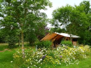 a garden with flowers in front of a cabin at Camping le Frêche à l'Âne in Pléboulle