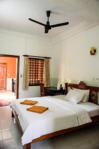 1 dormitorio con 1 cama blanca grande y ventilador de techo en Jasmine Lodge Siem Reap en Siem Reap