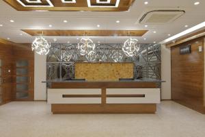 a hotel lobby with a reception desk and chandeliers at Hotel Silver Heights in Ahmedabad