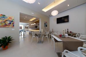 a dining room with white tables and white chairs at Artemide Hotel in San Vito lo Capo