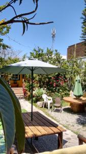 a wooden table with an umbrella and a bench at Hostal Maria Casa in La Serena