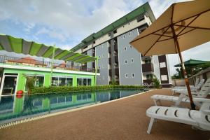 a hotel with a swimming pool with chairs and an umbrella at Gold Airport Suites in Lat Krabang