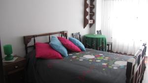 - une chambre dotée d'un lit avec des oreillers colorés dans l'établissement Apartamento Alegria, à Saint-Jacques-de-Compostelle