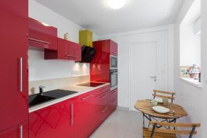 Corneille by Cocoonr في رين: مطبخ مع دواليب حمراء وطاولة خشبية