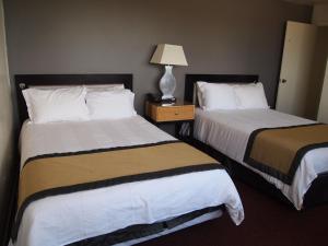 a hotel room with two beds and a lamp at Stamford Suites in Stamford