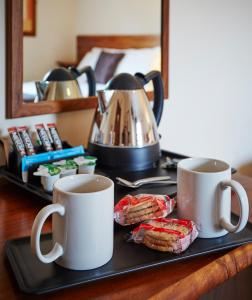 ヨービルにあるThe Terrace Lodge Hotelのコーヒーマグカップ2つとクッキーをテーブルに用意したトレイ
