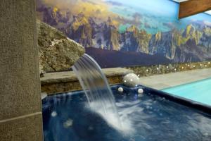 a hot tub with a water fountain in front of a mural at Hotel L'Equipe in Morzine