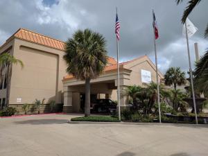 un edificio con una palmera delante de él en Country Inn & Suites by Radisson, Portland, TX, en Portland