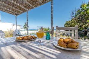 a table with two plates of bread and a glass of orange juice at Mandrakia Bliss House in Mandrakia