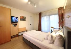 una camera d'albergo con letto e TV di Hotel & Wirtshaus Hansen a Bergisch Gladbach