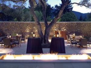 a patio with tables and chairs and a stone wall at Hotel Yountville in Yountville