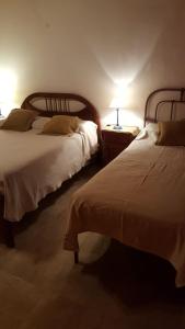 Dos camas en una habitación con dos lámparas. en Los Colorados Hostal en Angastaco