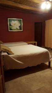 1 dormitorio con 1 cama blanca en una pared roja en Los Colorados Hostal en Angastaco