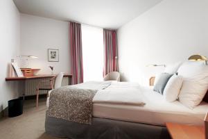 ヴェーゼルにあるHotel Haus Dudenの大きなベッドとデスクが備わるホテルルームです。