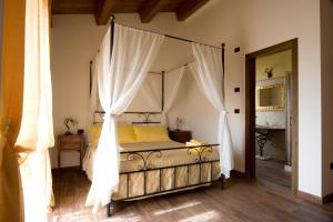 FrontinoにあるAgriturismo La Spiga D'Oroのベッドルーム(白いカーテン付きの天蓋付きベッド1台付)