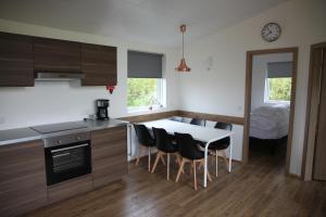 een keuken met een tafel en stoelen en een slaapkamer bij Kjarnagerdi Cottages in Laugar