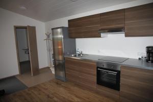 uma cozinha com armários de madeira e um frigorífico de aço inoxidável em Kjarnagerdi Cottages em Laugar