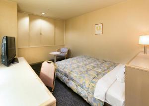 a hotel room with a bed and a flat screen tv at Tsubamesanjo Washington Hotel in Sanjo