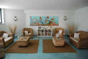 una sala de estar con sillas y mesas de mimbre y una pintura en Villa Nettuno Residence, en Giardini Naxos