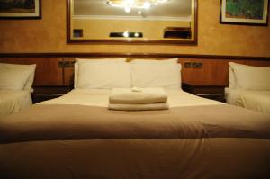 فندق كريكل وود لودج  في لندن: سرير عليه كومه من المناشف